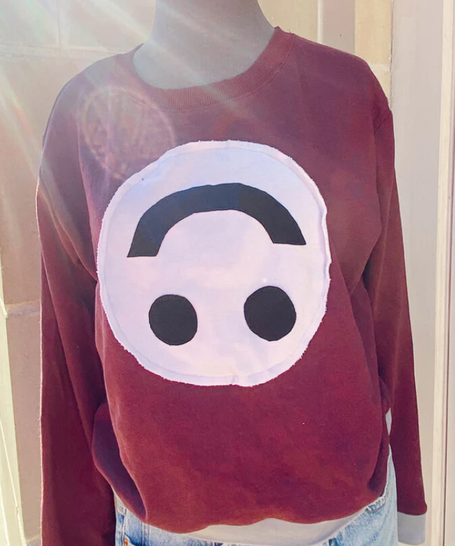 Red sweatshirt with a sewed-on upside down smiley face, made by Miller