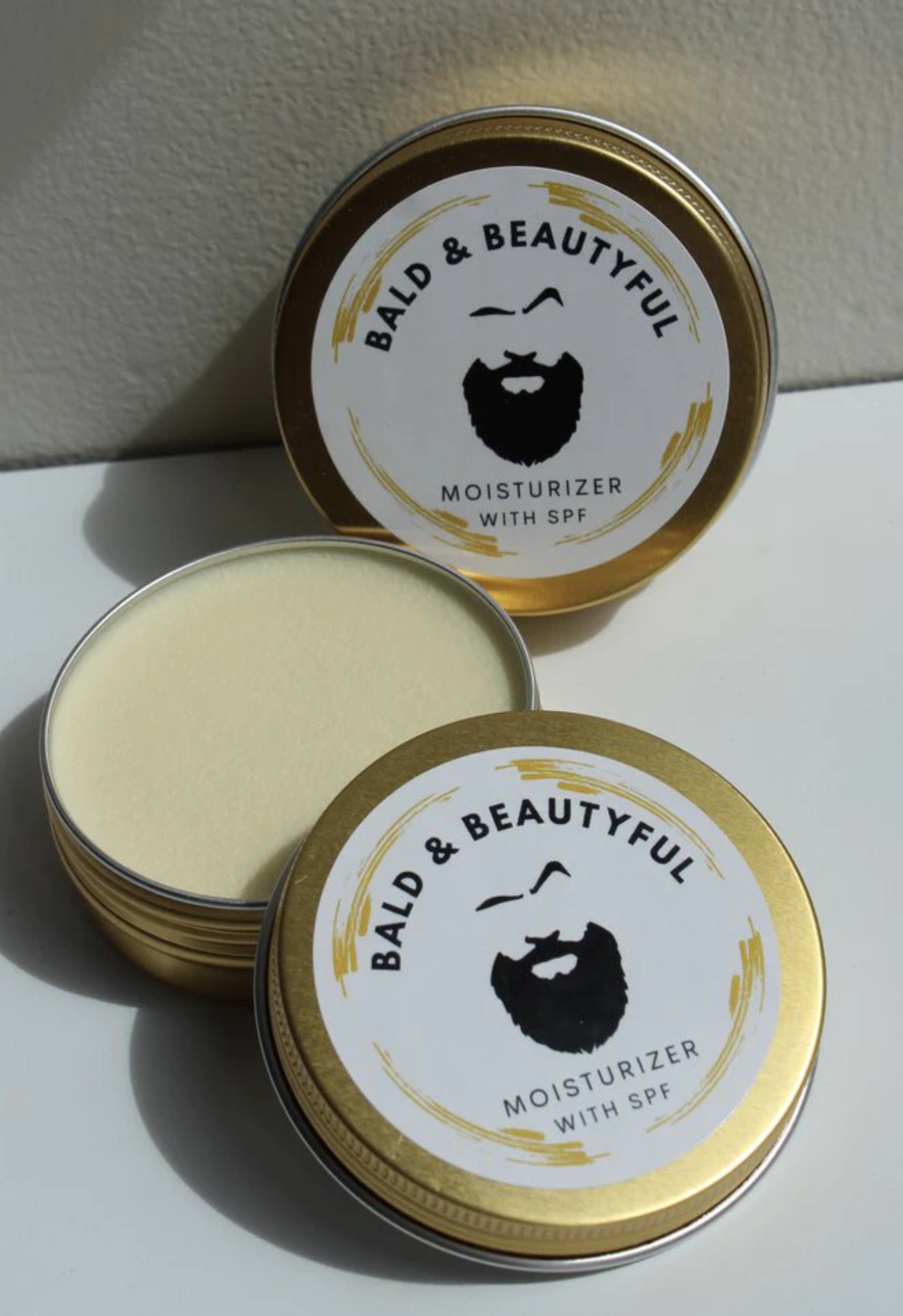 Open gold tin of Bald & Beautyful moisturizer 