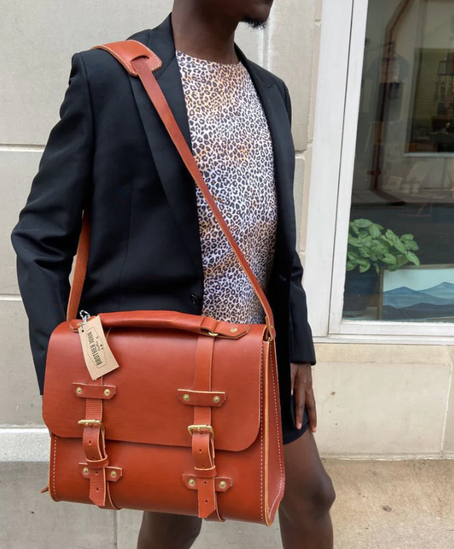 Model carrying orange leather messenger bag, made by Brother John Leather