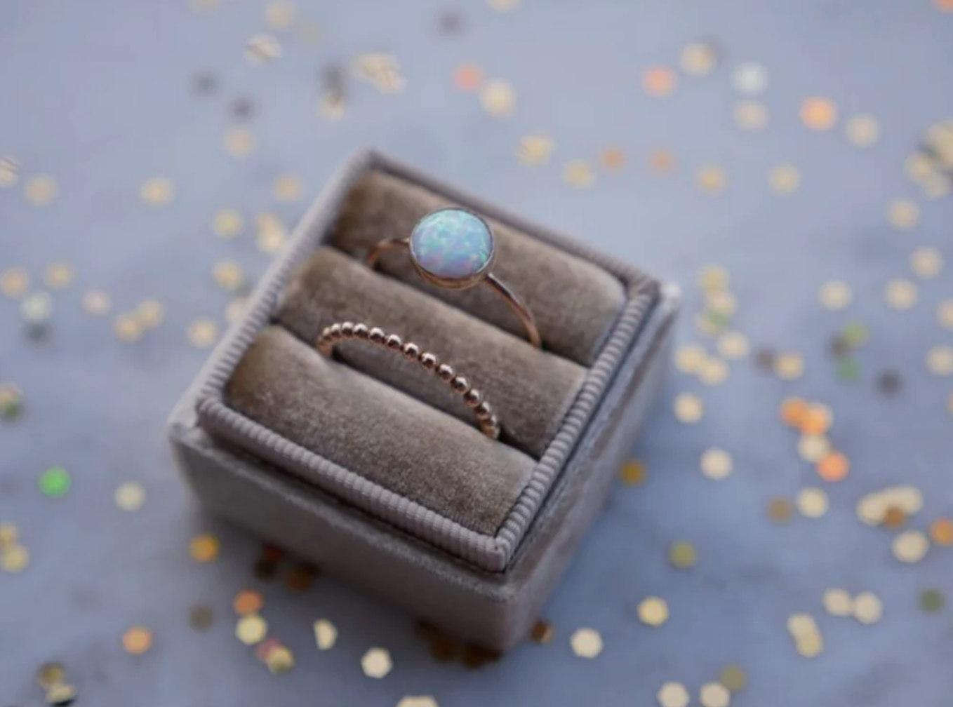 two rings, one opal one ridged, in ring box surrounded by glitter, created by Emily Warden designs