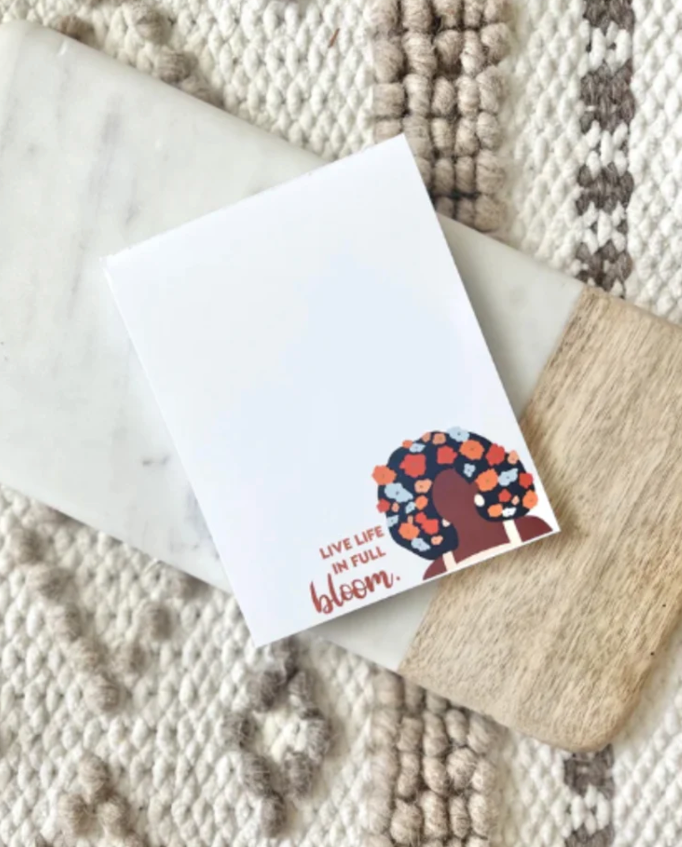 "Live life in full bloom" notepad featuring a black woman with flowers in her hair, created by K Ligg Co