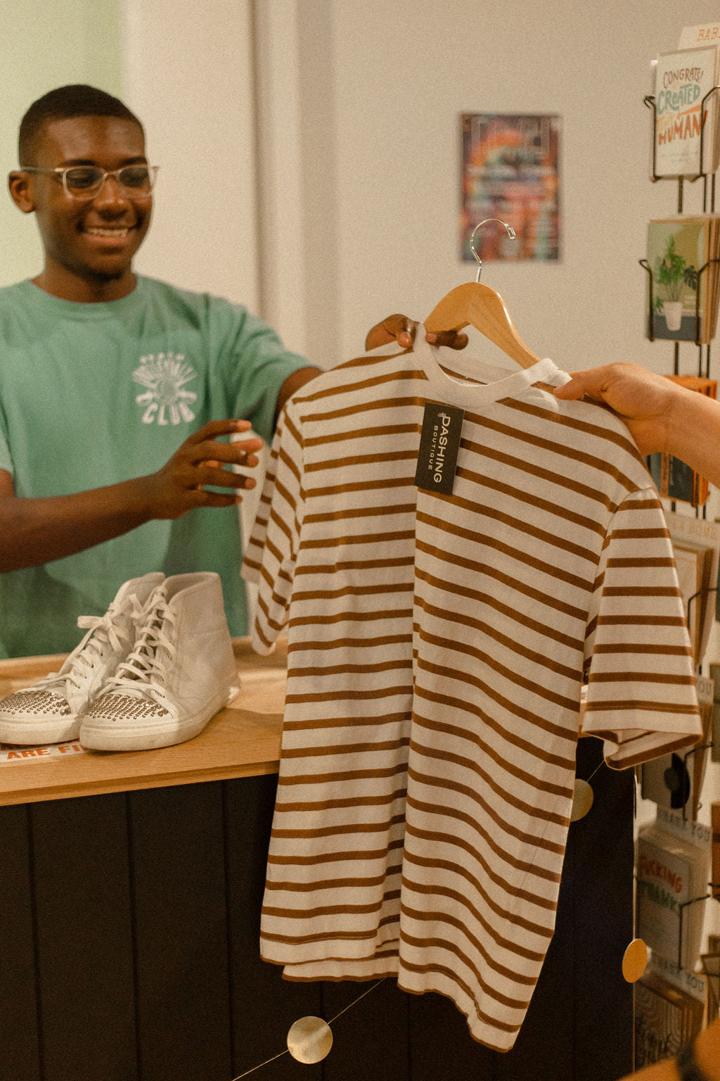 Person checking out at Darling x Dashing in downtown charlottesville. They are handing a striped shirt to a smiling employee